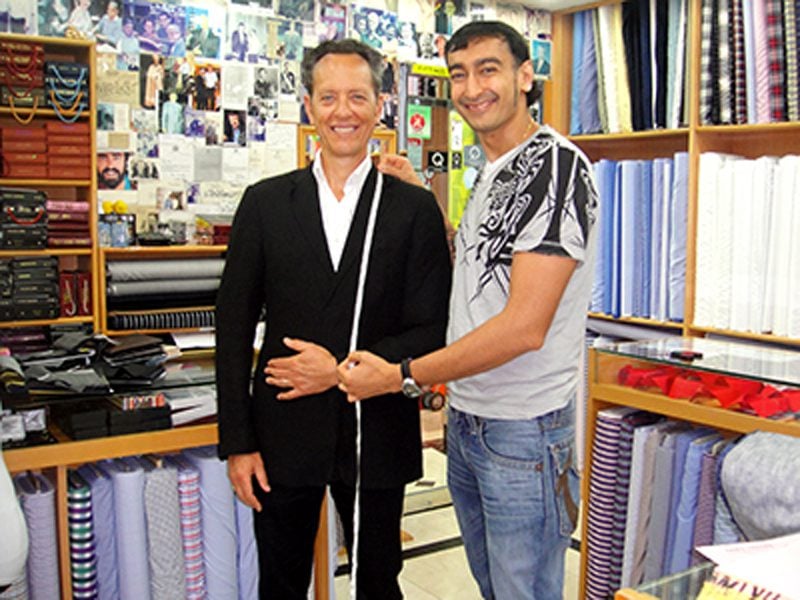 Richard E Grant in store at Sam's Tailors, measuring up with Roshan Melwani